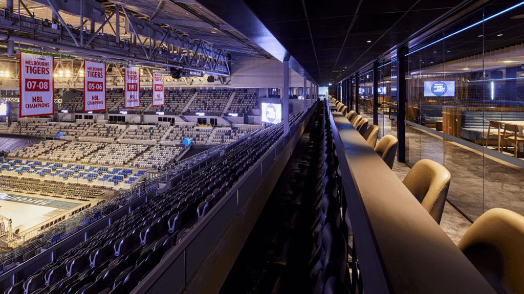 A group of people enjoying food and drink at a corporate event in a John Cain Arena suite.