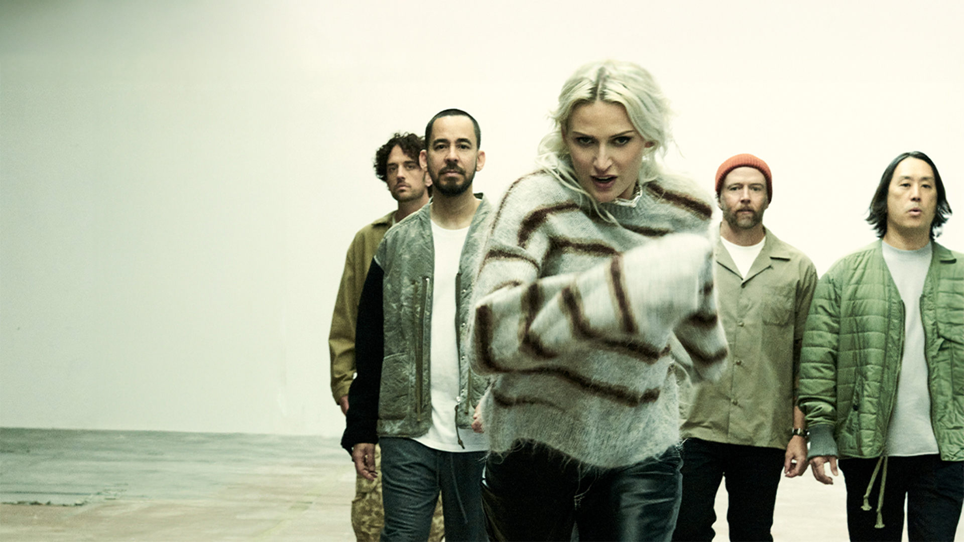 Linkin Park band members gathered in a room, standing together and interacting with one another.