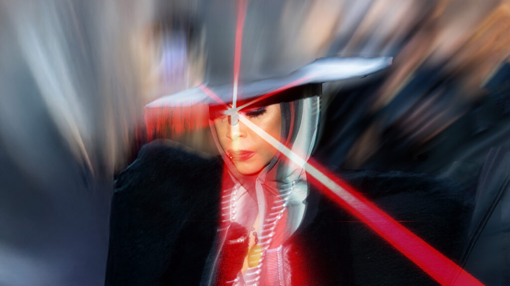 Singer Erykah Badu wearing a hat and posing with lasers.