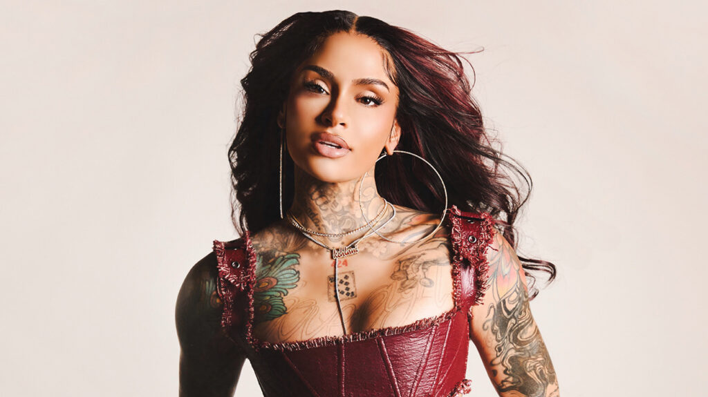 Kehlani wearing a reda dress, posing confidently against a neutral background.